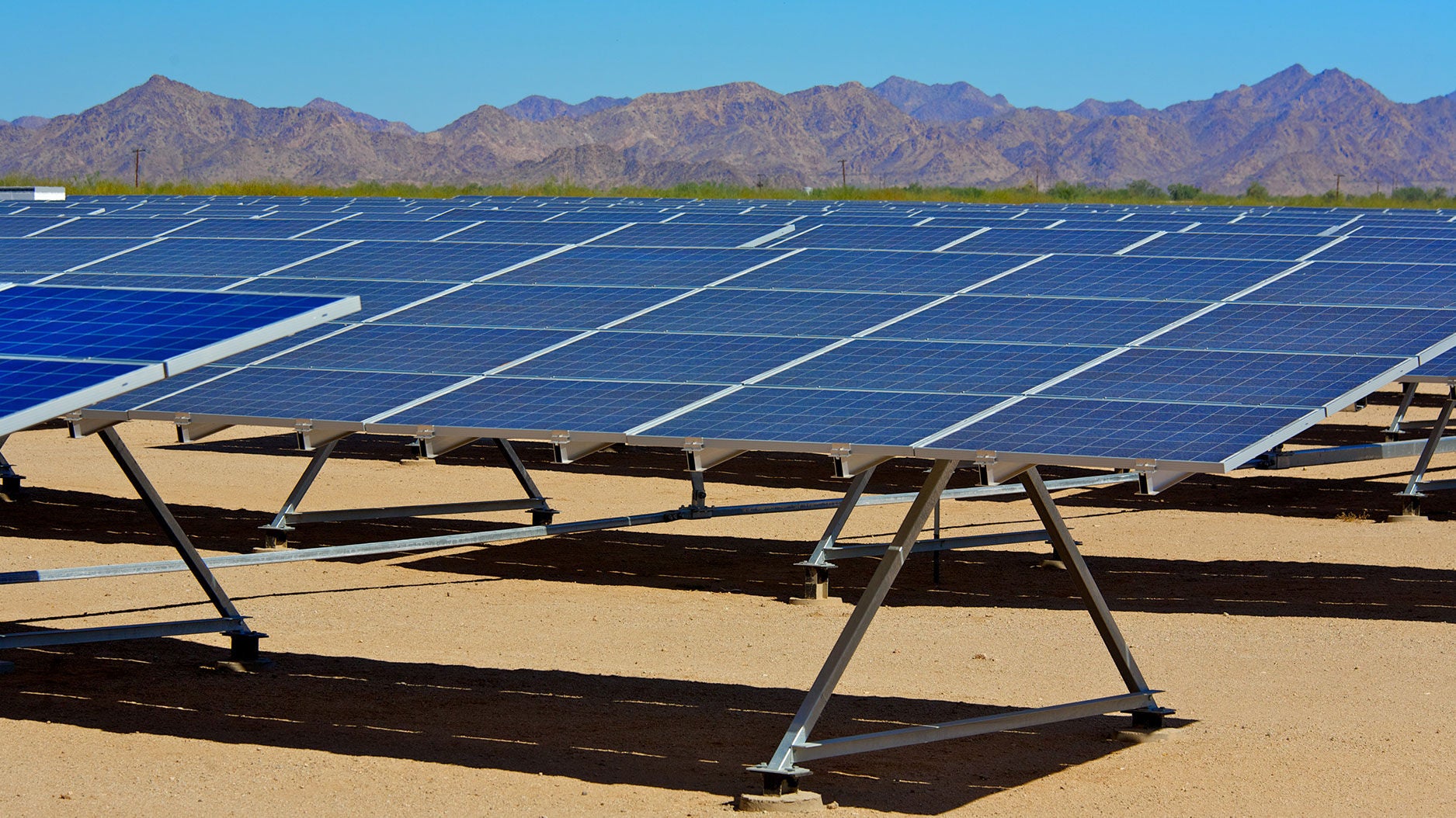 solar panels in open field with mountain range in background