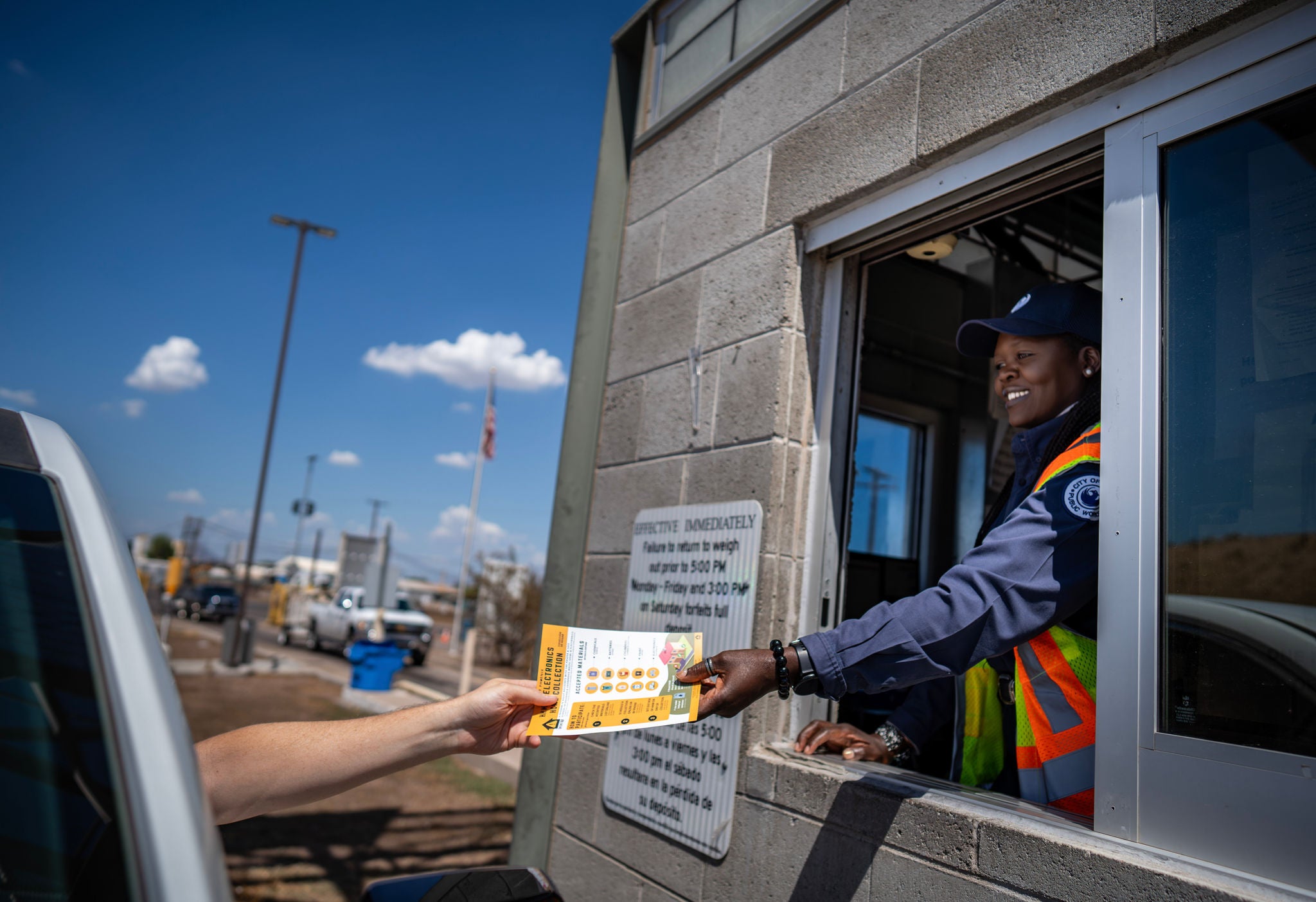 A Publi Works employee at the drive-up window gives a driver information about the 27th Avenue Transfer Station