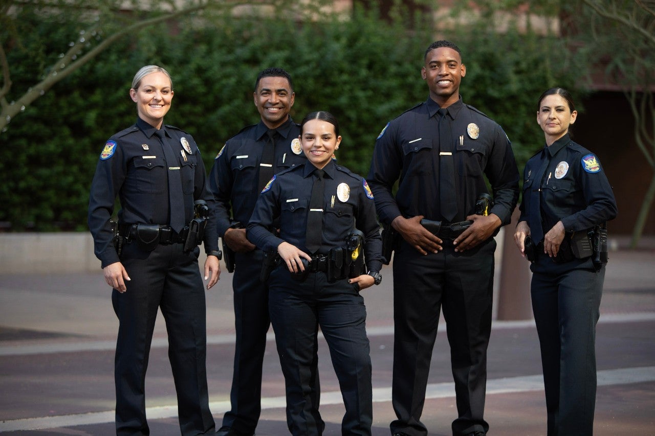 Five officers posing in full uniform.
