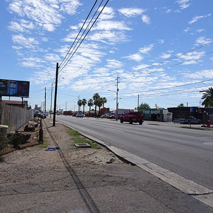 Straight stretch of road, bookmarked by telephone wires and no visible lane markings.