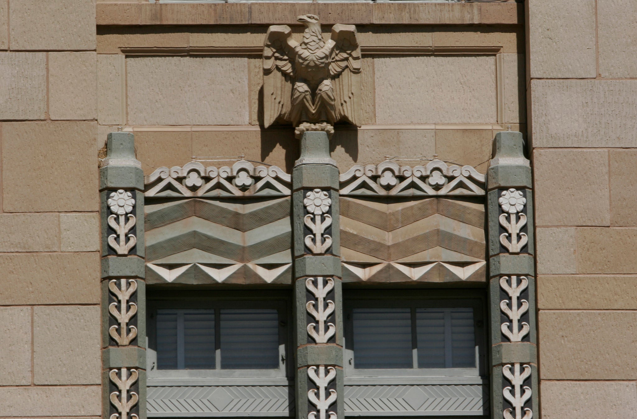 Image of historic windows on Phoenix City Hall. They have decorative stone trim and a phoenix bird.