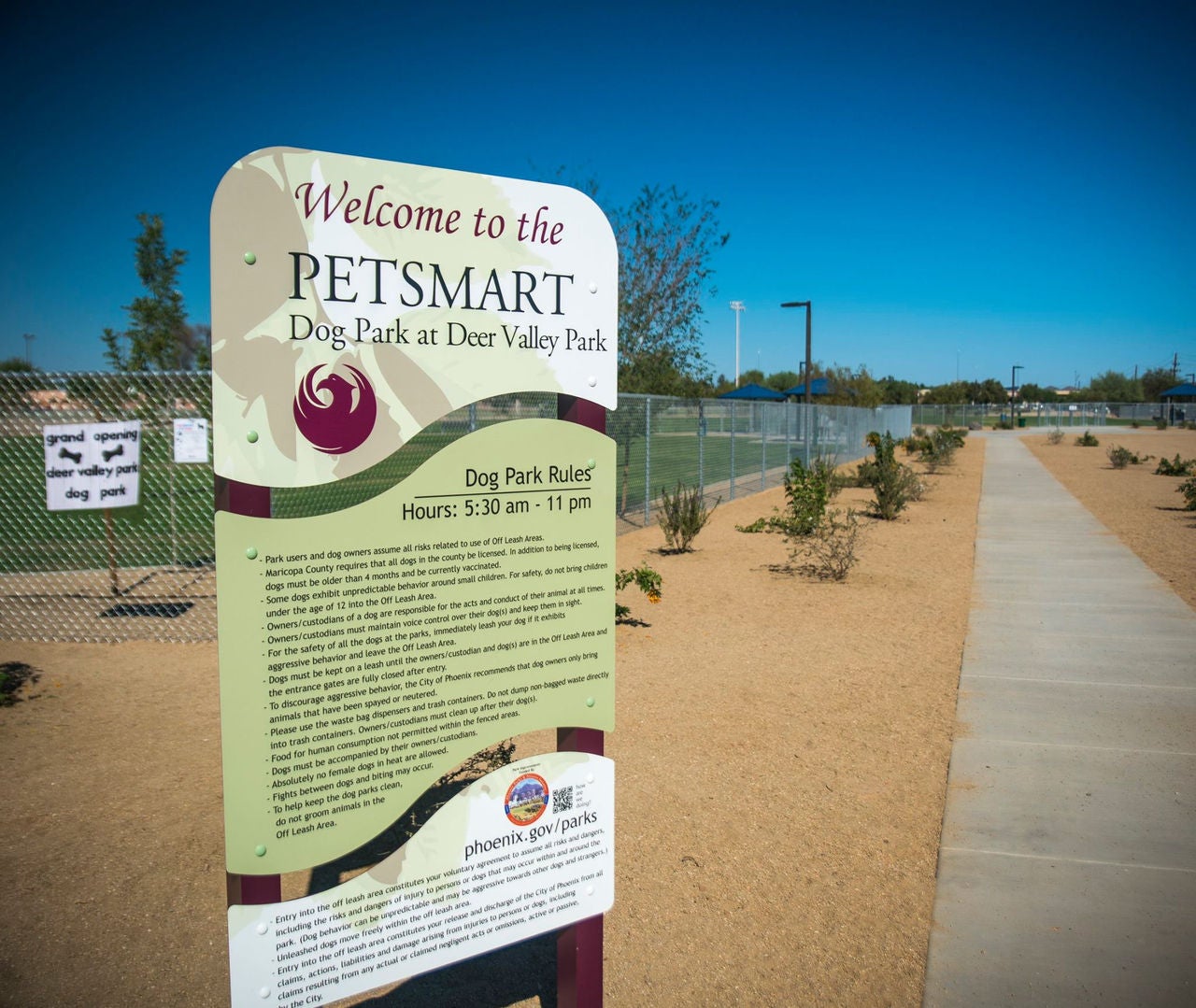 Welcome sign for Deer Valley Dog Park with a fenced in area in the background.