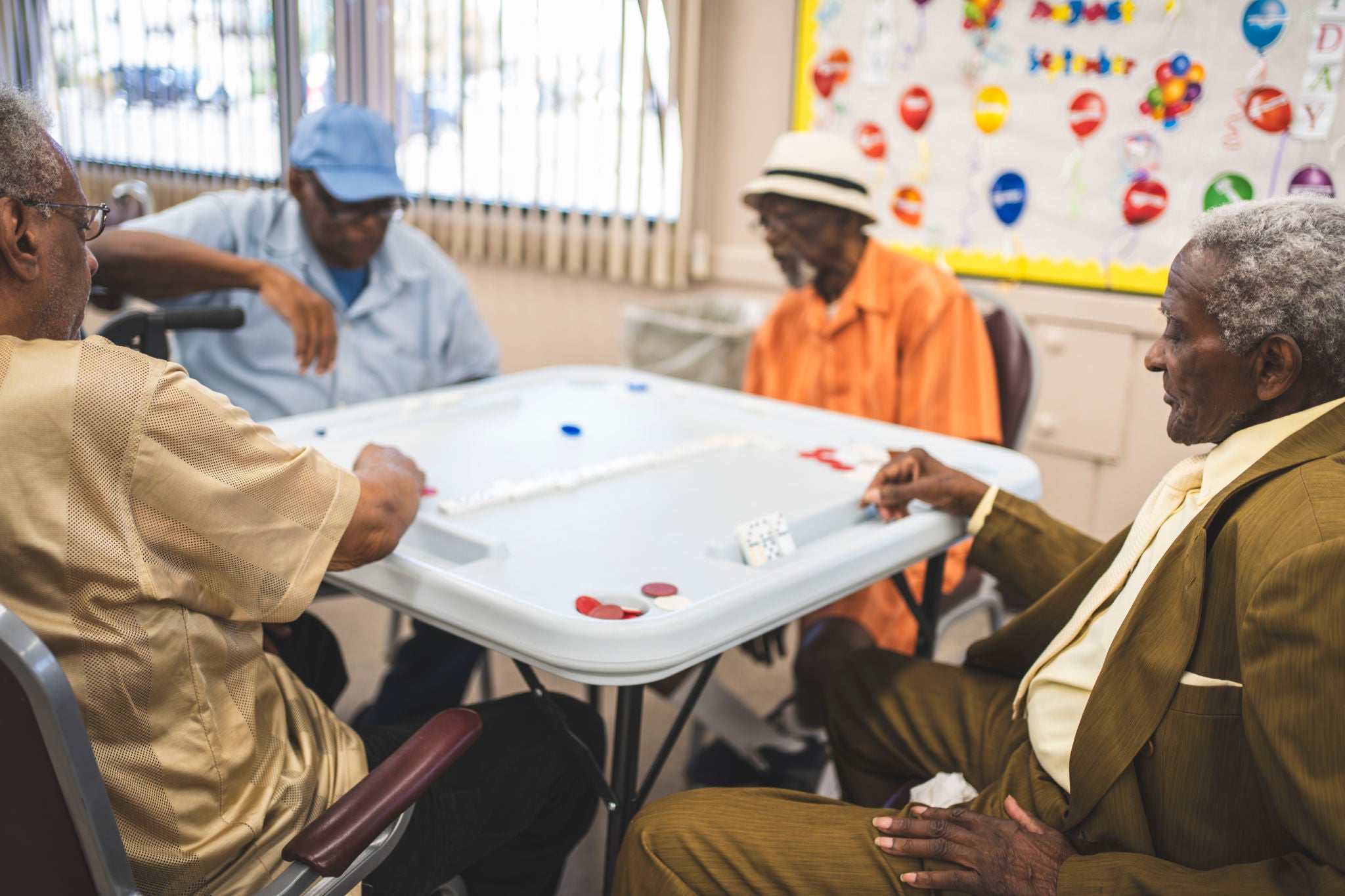 A group of older men sit at a table and play games.