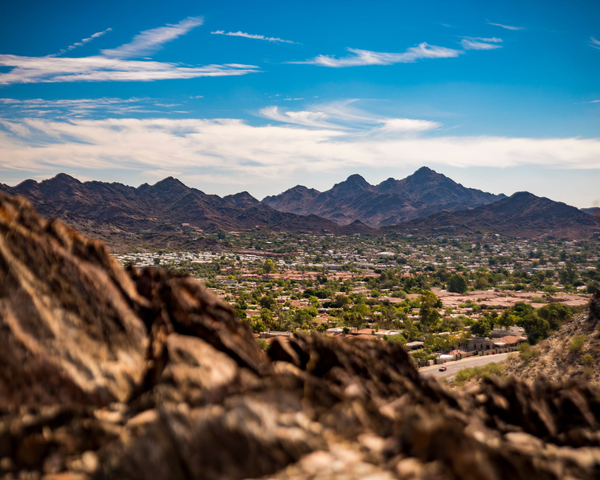 Photo of North Mountain, with rocks in the foreground, suburban neighborhoods below, and more mountains in the distance.