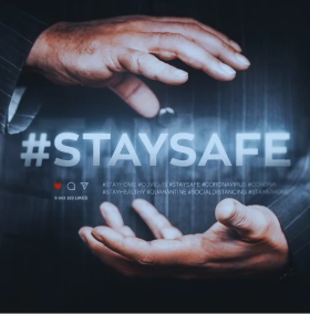 A man in a suit stands facing forward. His right hand is cupped and facing down in front of his body. His left hand is also cupped, but it faces up and is positioned just below his right hand. Between his hands, there is a floating image of a pound sign (£) and the words "STAY SAFE." The image suggests that he is using his hands to emphasize the importance of safety.