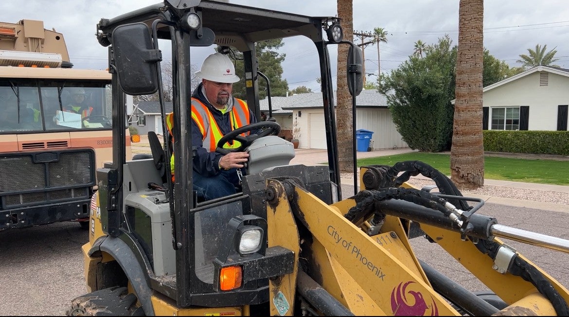 A Public Works employee collects bulk trash with a tractor. 