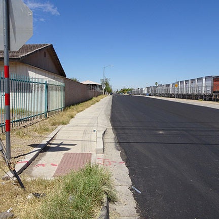 A paved road with a sidewalk and no visible lane markings on the road.