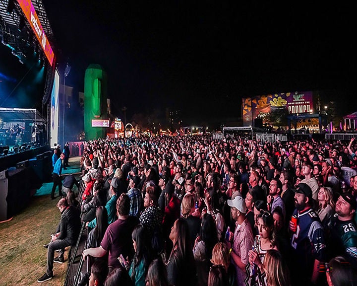Large crowd attending an outdoor night concert with a brightly lit stage at Hance Park