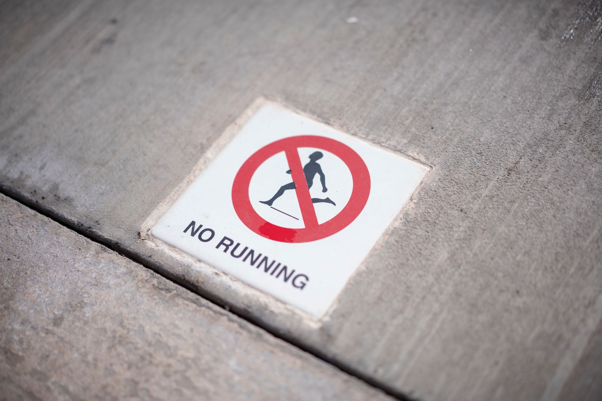 Photo of a warning sign on the ground that says "no running"