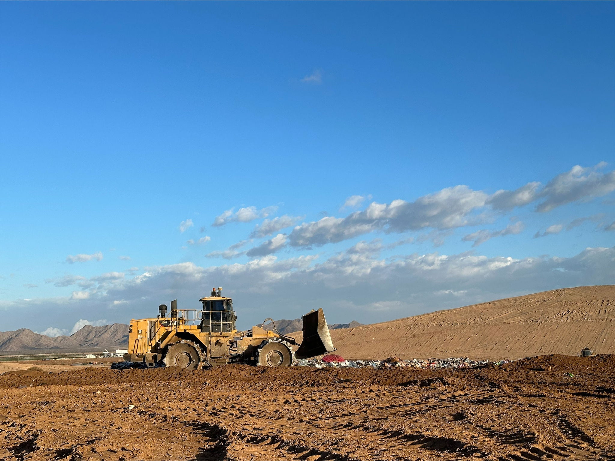 A loader drives on top of the landfill