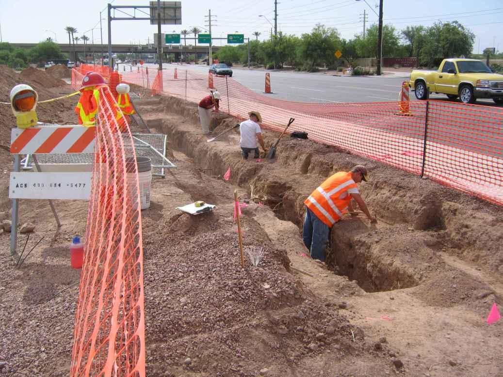 Archaeologists working on a data recovery along a busy street