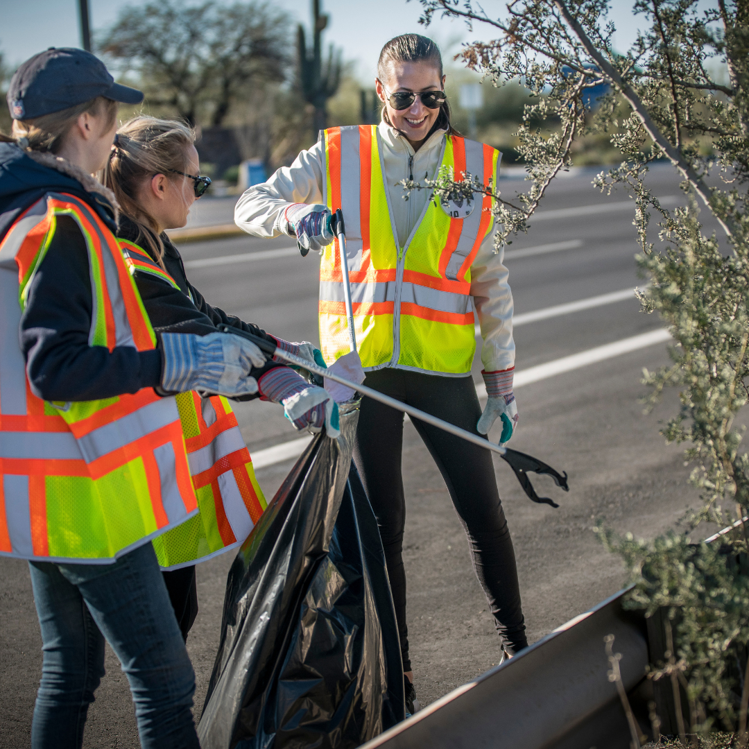 people in neon vests picking up trash.