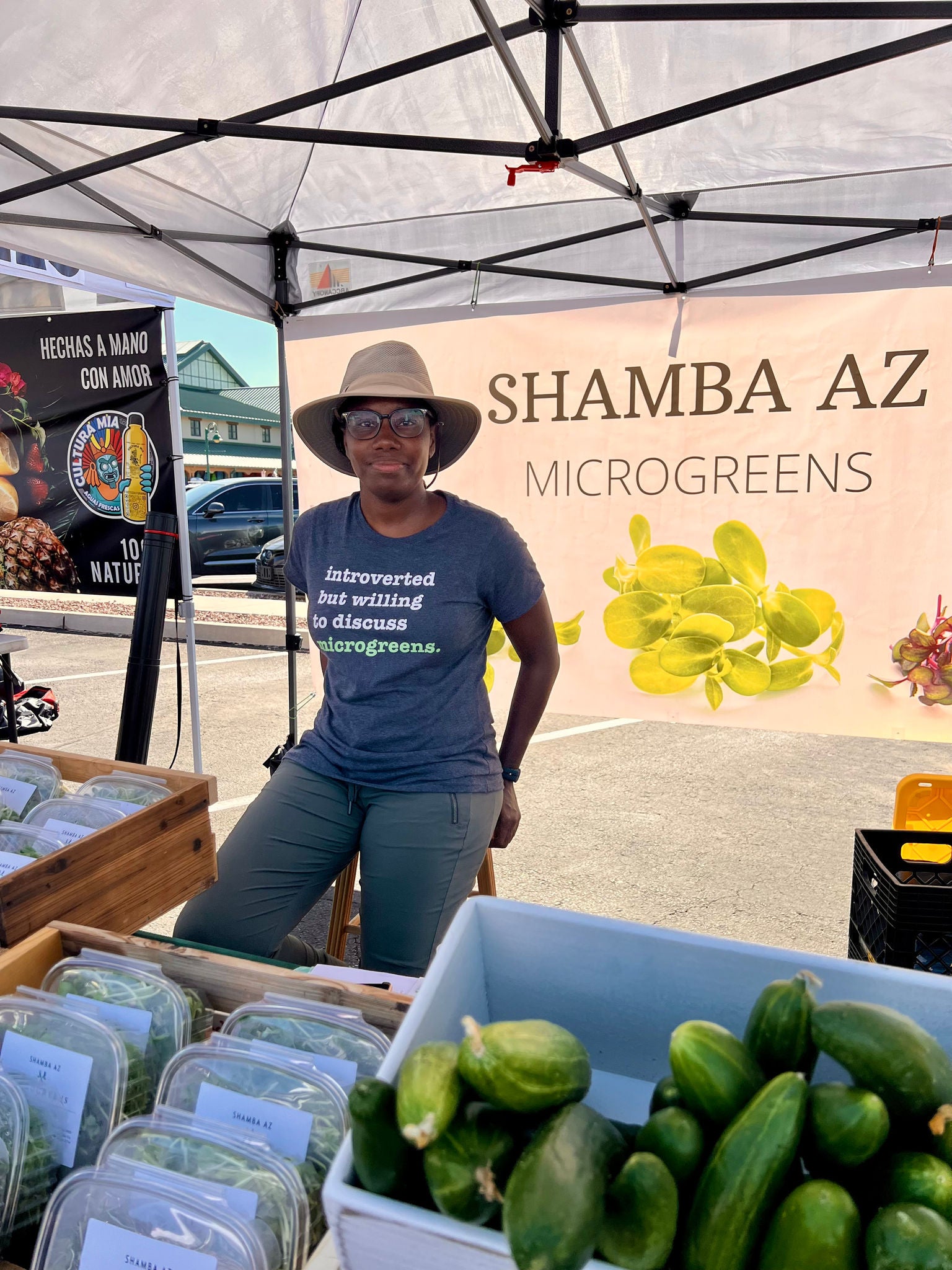 Avrile Remy, founder of Shamba AZ sits at her vendor booth at a farmer's market