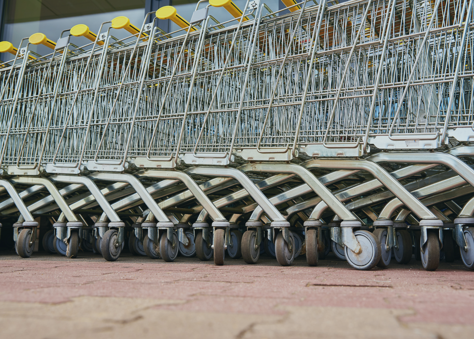 A close-up of stacked shopping carts with yellow handles. 