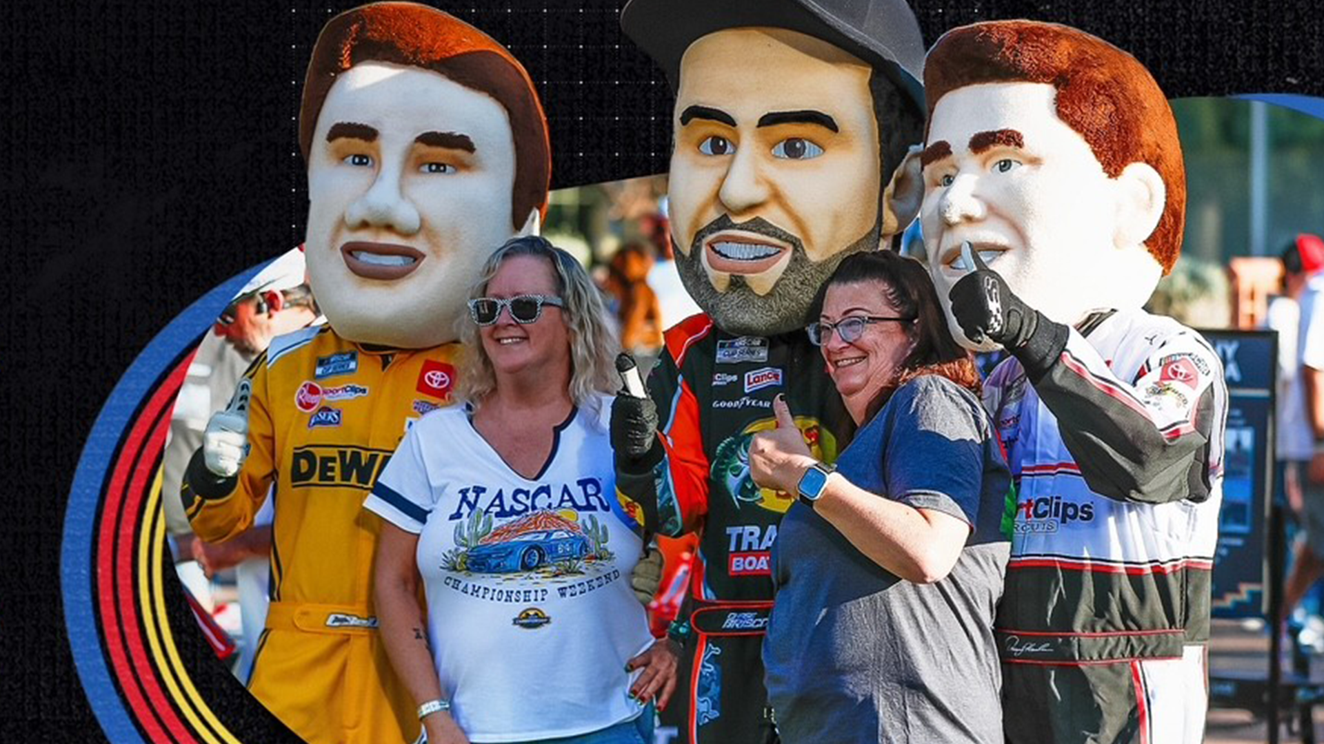 Two women stand in front of mascot NASCAR drivers at an event.
