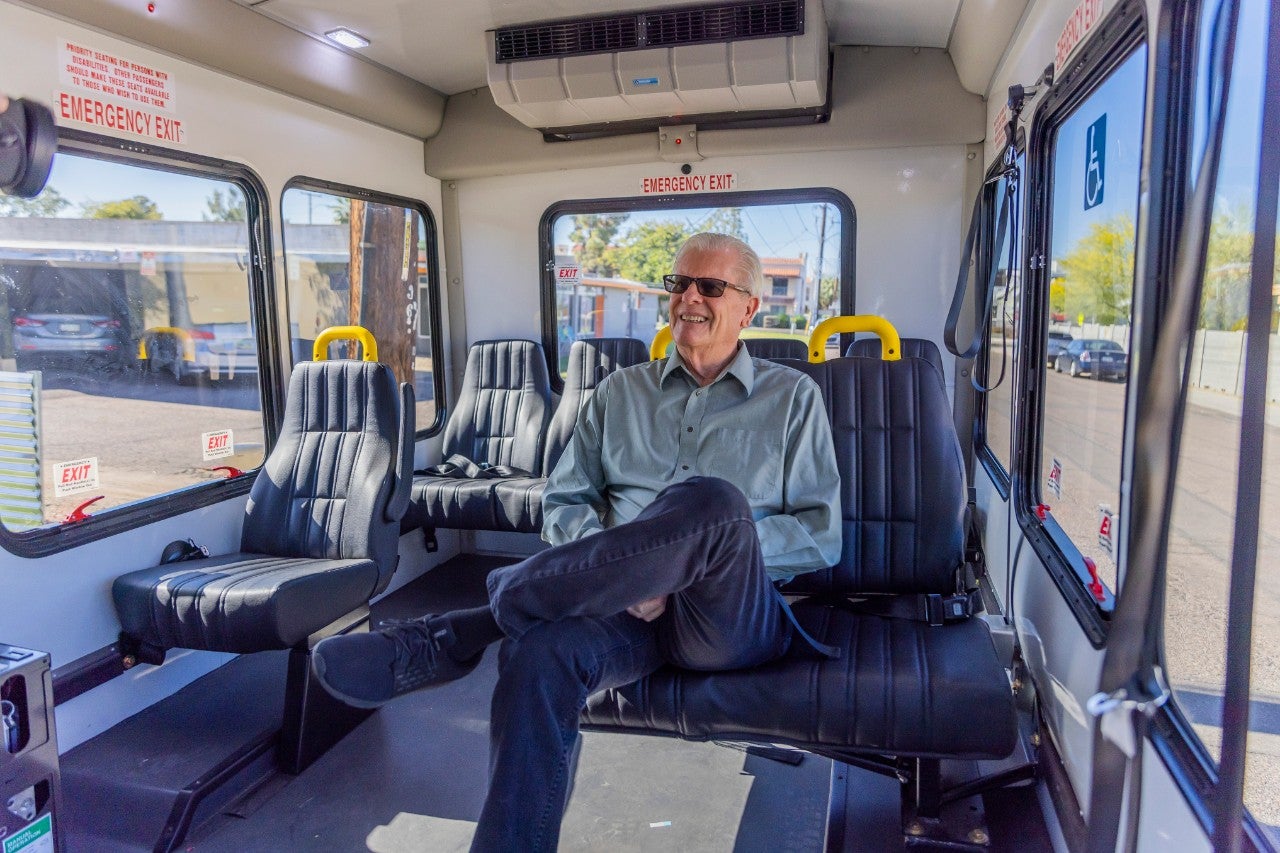 An older man sits on a bus.