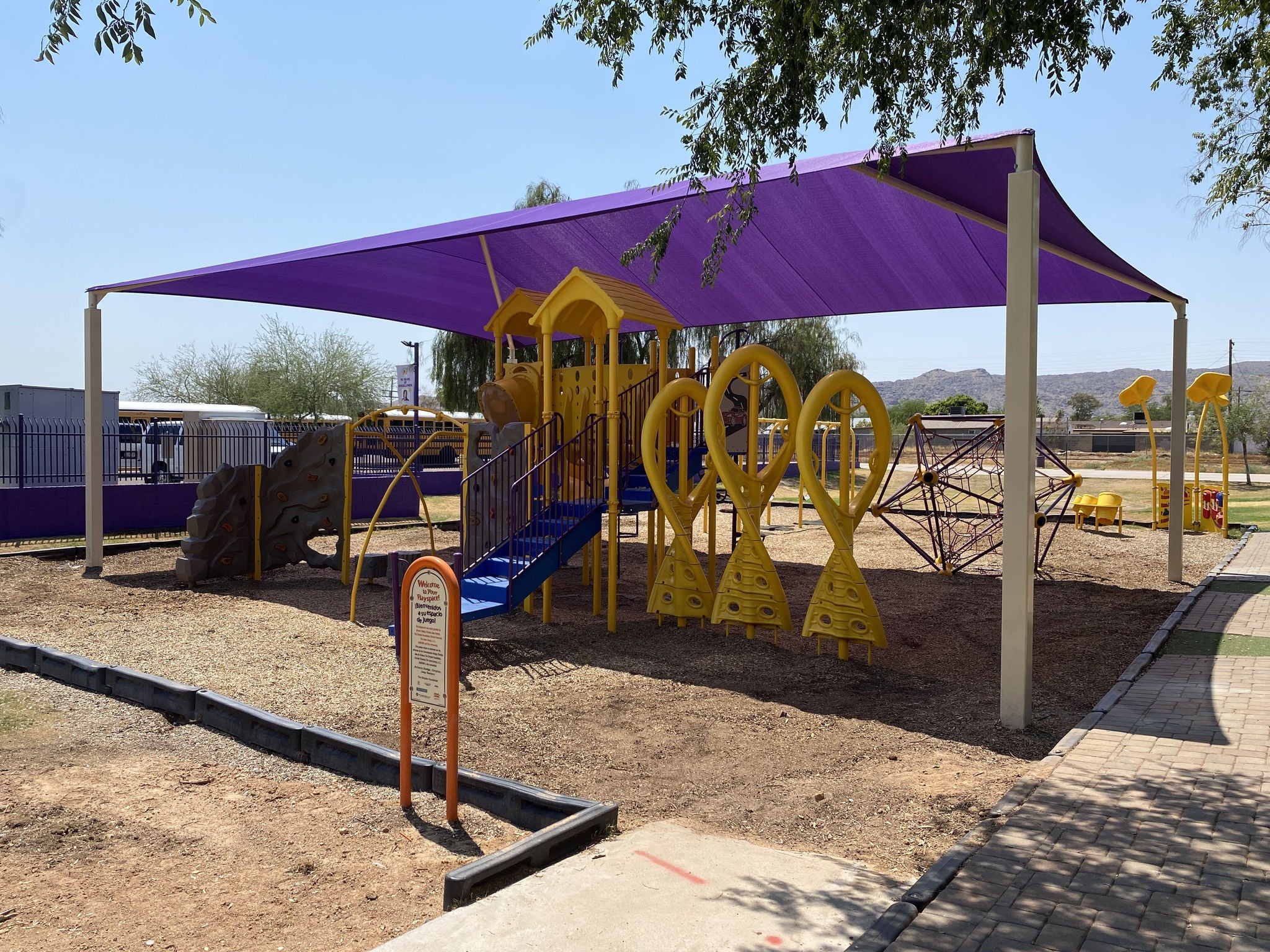 photo of purple shade structure over yellow playground