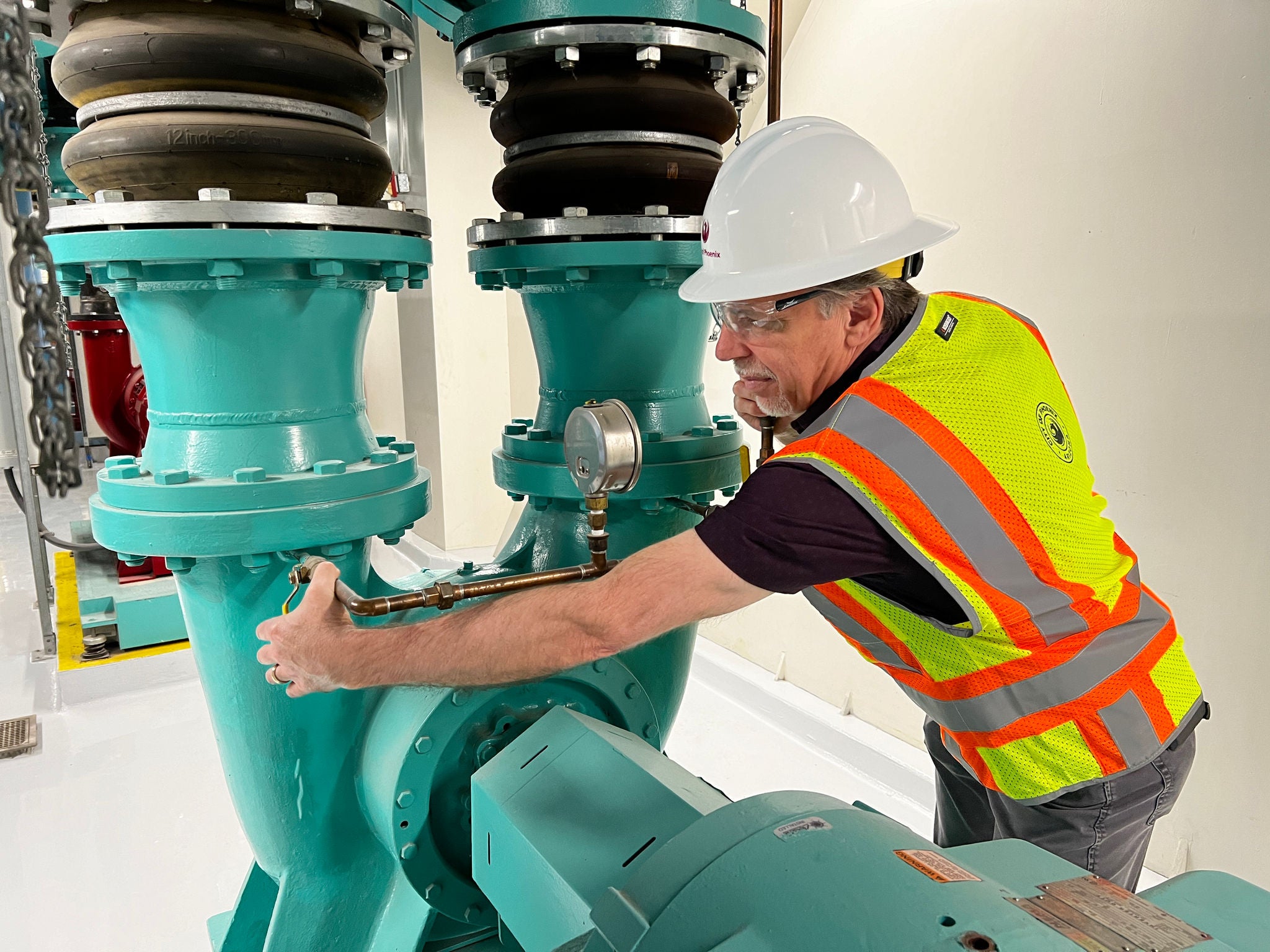 A BEO checks valves and gauges in a City mechanical room.
