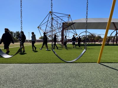 Photo of kids enjoying their newly renovated school playgound, with swings on the foreground.