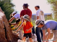 Children and adults mudslinging the mound for International Archaeology Day