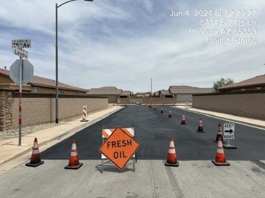 Photo of a street blocked off by orange traffic cones and a sign that reads fresh oil
