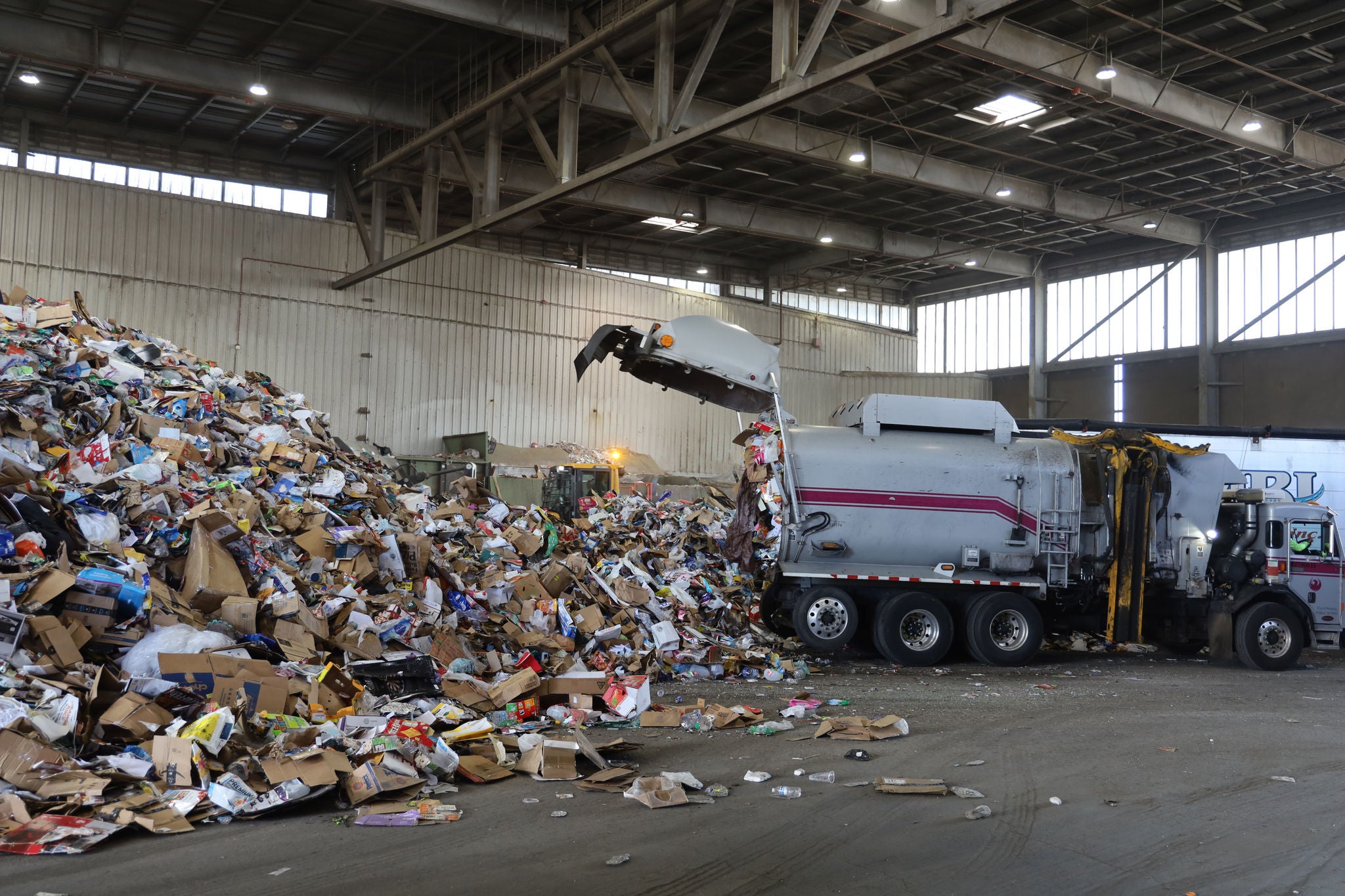 A solid waste collection truck dumps recyclables into a giant pile before they get sorted at the Materials Recovery Facility.