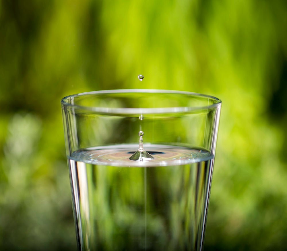 A drop of water falls into a clear glass.