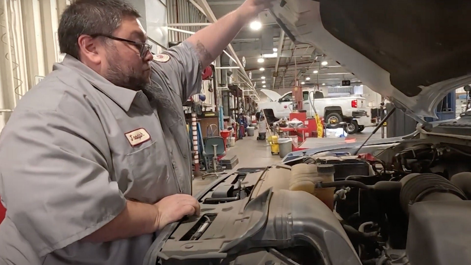 Fleet Apprentice opening the hood of a vehicle to inspect engine