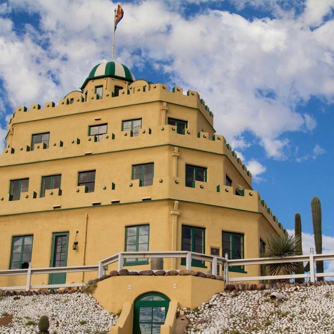 A yellow stone building in the style of a castle with turrets along the walls.