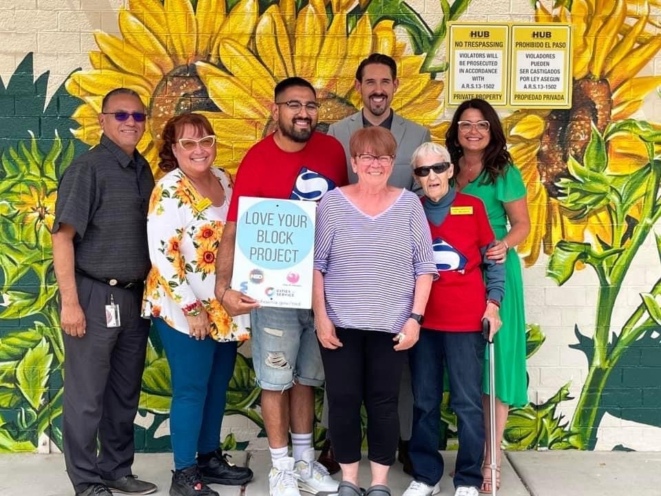 Elected official, Neighborhood Services team, and residents pose in front of an eye-catching sunflower mural, designed by a local artist.