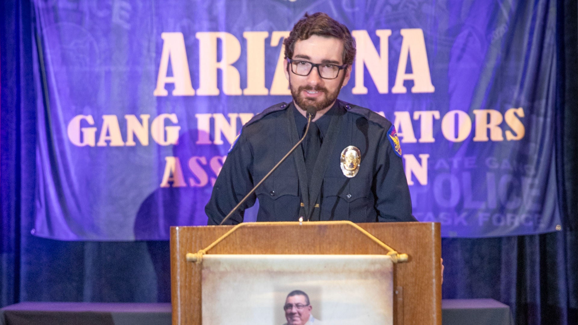Tyler Moldovan stands behind a podium after leaders from the Arizona Gangs Investigators Association present him with the innagural Tyler Moldovan Award for Valor