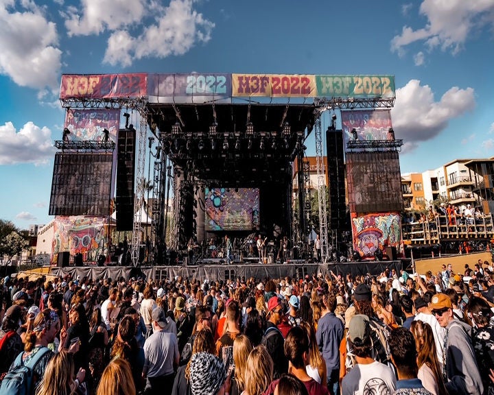 Daytime outdoor concert with a large crowd and colorful stage banners labeled 'H3F 2022.