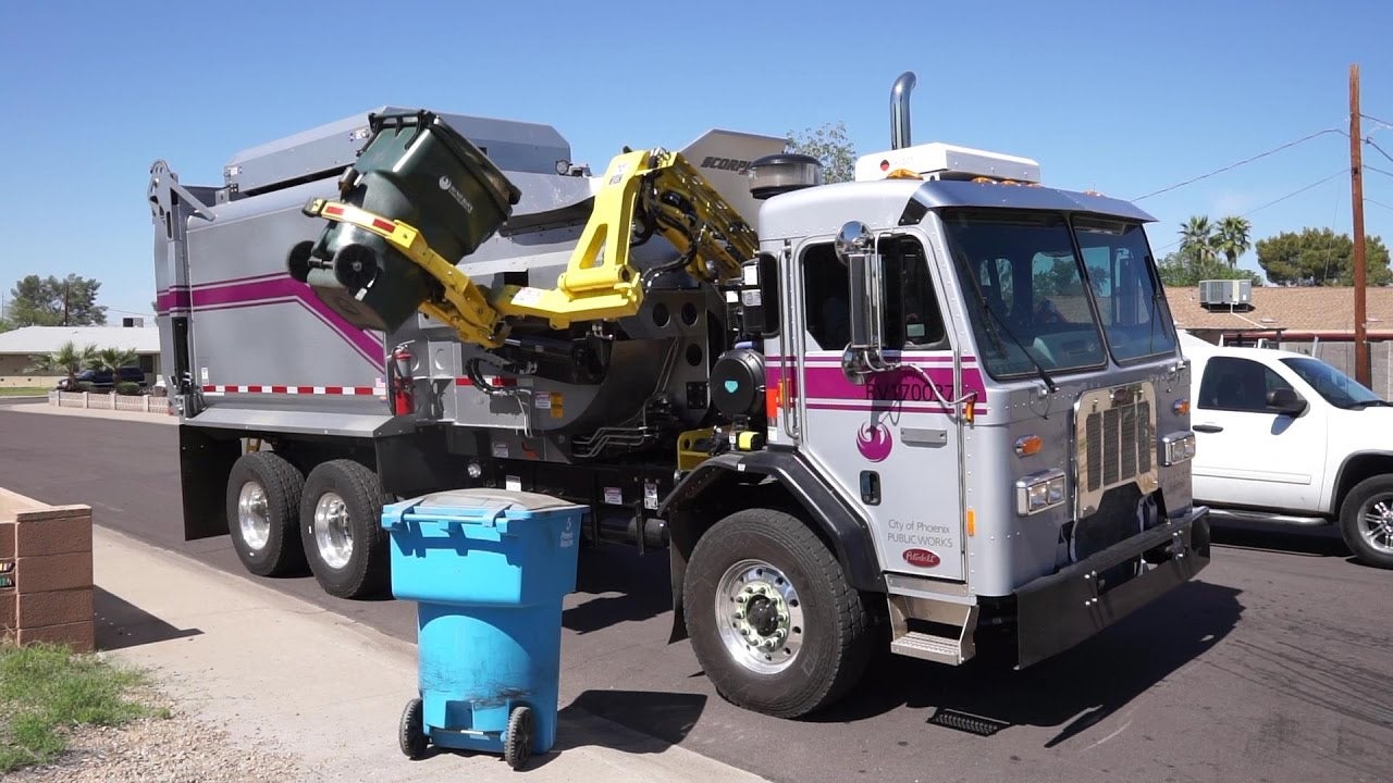 A City of Phoenix Public Works truck picks up a residential recycling bin from the curbside.