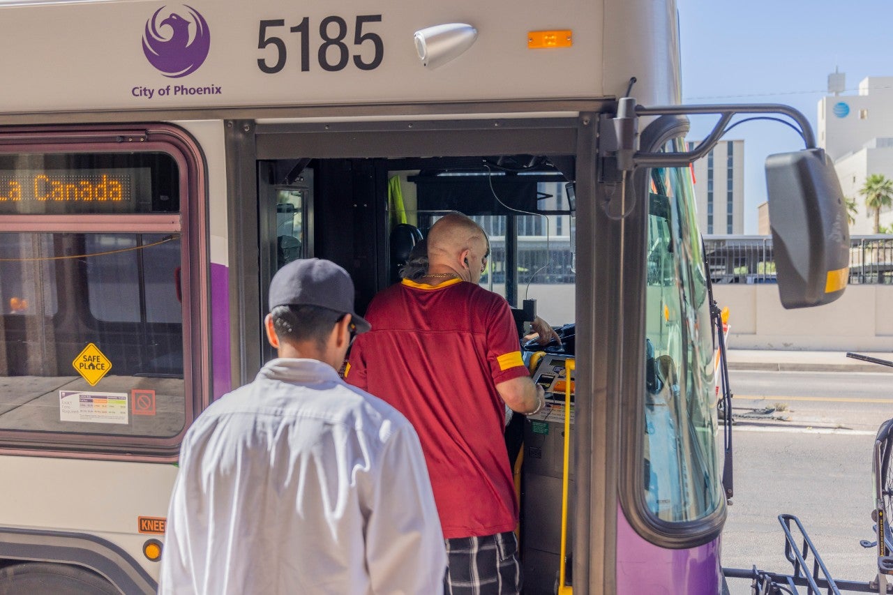 Two passengers boarding a City of Phoenix bus.