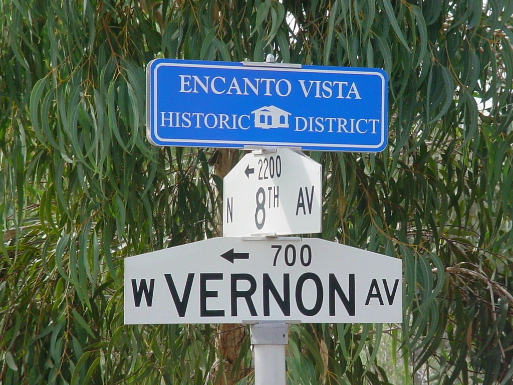 Street signs reading "ENCANTO VISTA HISTORIC DISTRICT", followed by signs for 8th Ave and Vernon Ave.