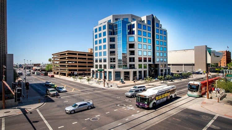 A street intersection in Phoenix with cars and buses on the roads.
